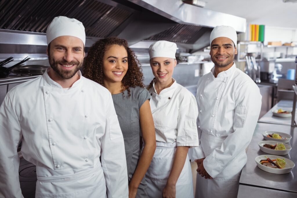 Restaurant kitchen staff standing together in a line smiling